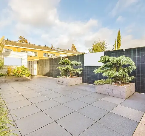 Modern outdoor patio with large pavers and landscaped planters