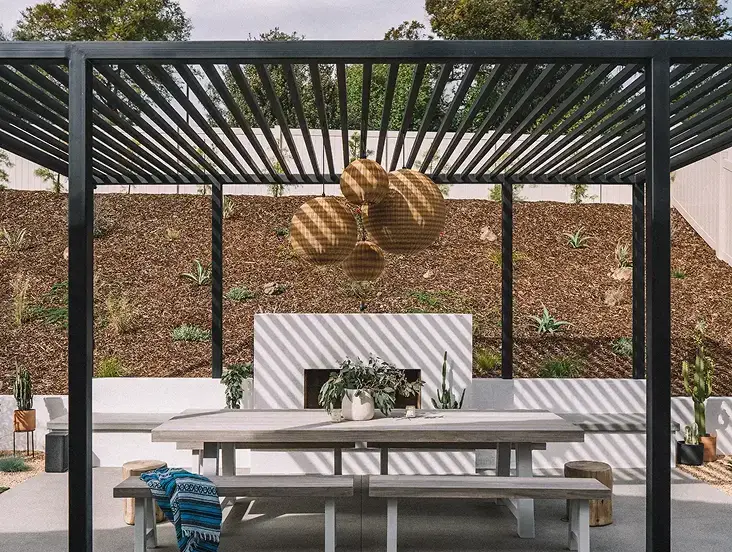 Modern outdoor pergola with dining table and landscaped yard