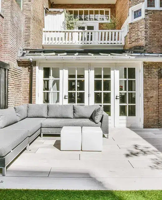 Outdoor patio with paver flooring and sectional seating beside a brick home